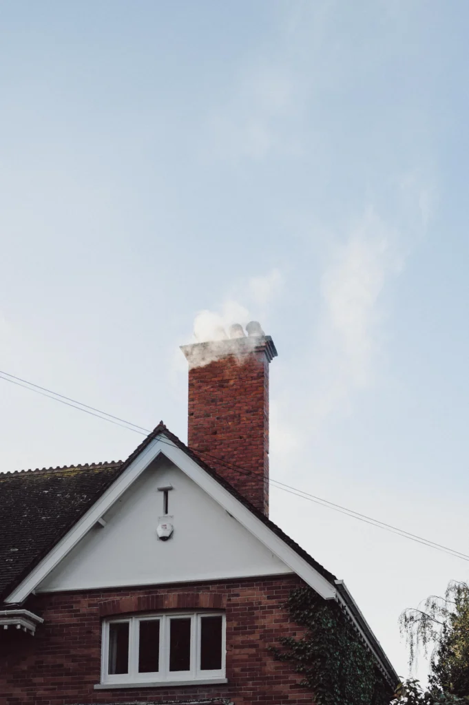 Brick chimney on a house roof against a pale sky