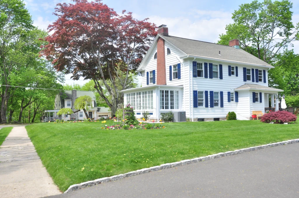 Colonial-style house with a brick chimney and lawn