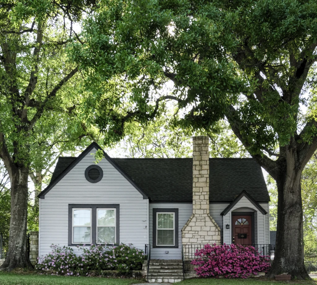 White house with a brick chimney among green trees