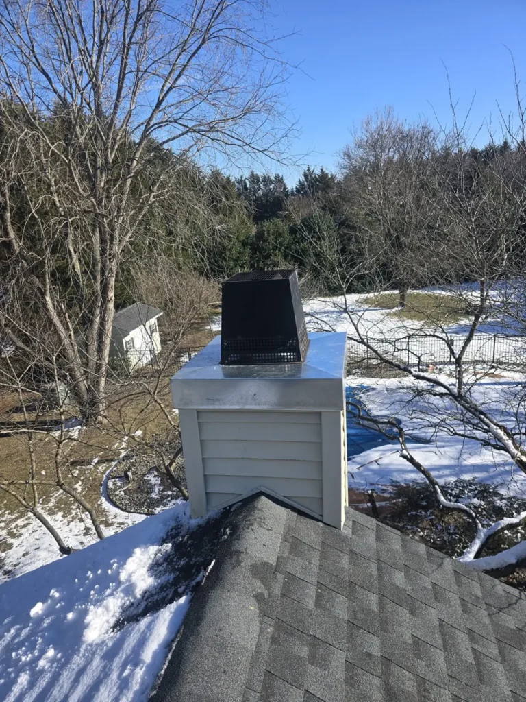Metal chase cover beneath a black chimney termination in Shamong