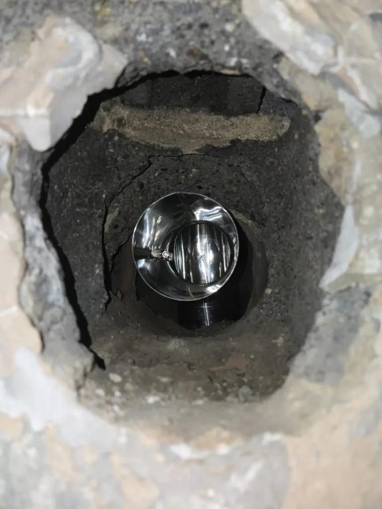 Metal liner fitting visible through a chimney wall opening in Fieldsboro