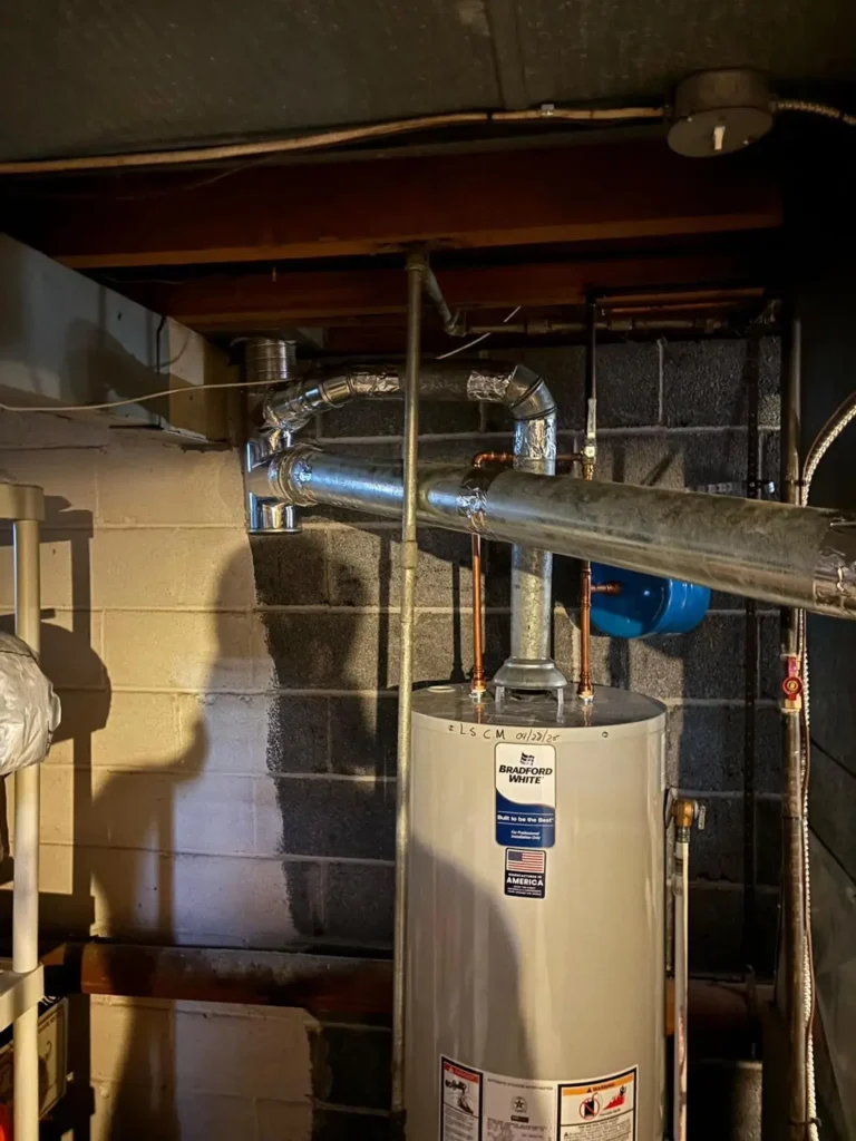 Basement vent piping and chimney liner connection beside a water heater in Flemington