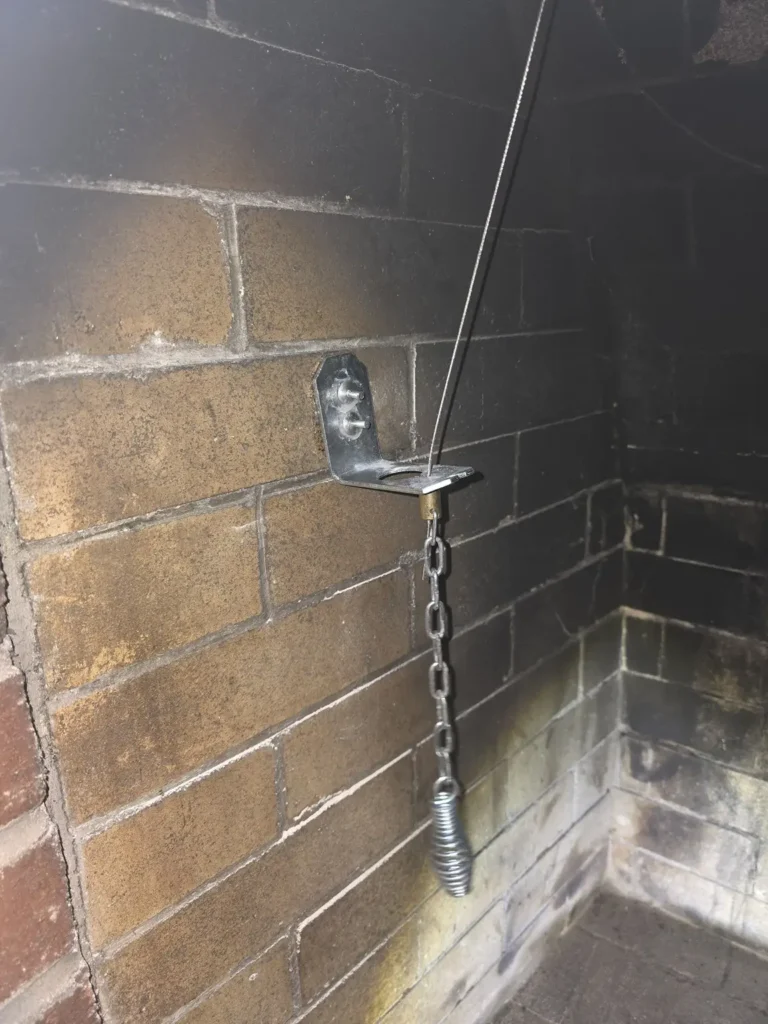 Damper control bracket and chain inside the Milltown fireplace