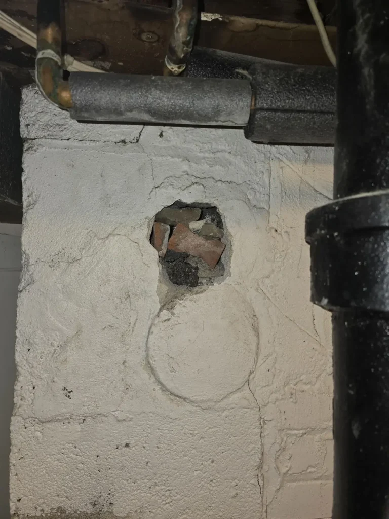 Open area in chimney masonry beside vent piping in Union