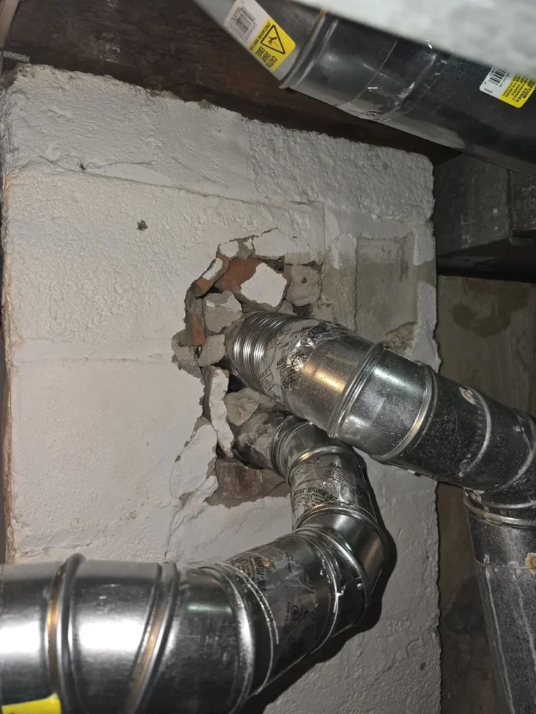Vent connections and exposed masonry at a Union chimney wall