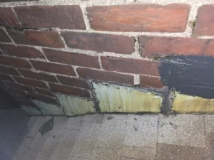 Metal flashing and roof shingles at the brick chimney in Milltown